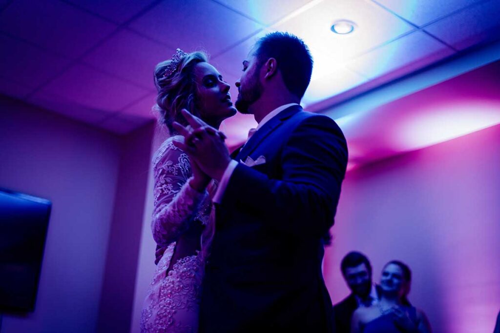 Newlyweds dance in purple lighting.